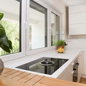 U-shaped white kitchen with Bora stove with built-in horizontal extractor, white Corian countertop seamlessly integrated with a Corian sink, functional backsplash with a rail for hanging small kitchen utensils, and a floor-to-ceiling wall cabinet