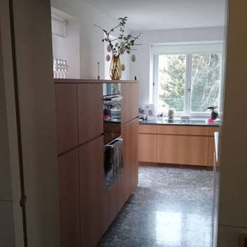 Overview of the T-shaped kitchen with wooden fronts and built-in oven and microwave, as well as Bora cooktop.