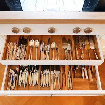 Open drawers with beautiful silver cutlery in natural wood drawer inserts, Bora controls, and Bora stove with built-in extractor in the countertop