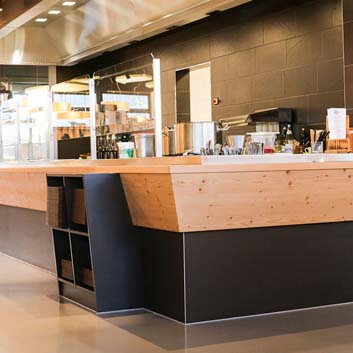 Organic supermarket in Germany, lunch counter, large gray and wooden block counter with an open shelf at the front for lunch trays