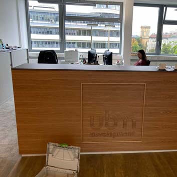 Kleine Bürotheke mit durchgehendem Holzstrukturbild, Logo in Holzoptik auf die senkrechte Fläche geklebt, dunkle Platte